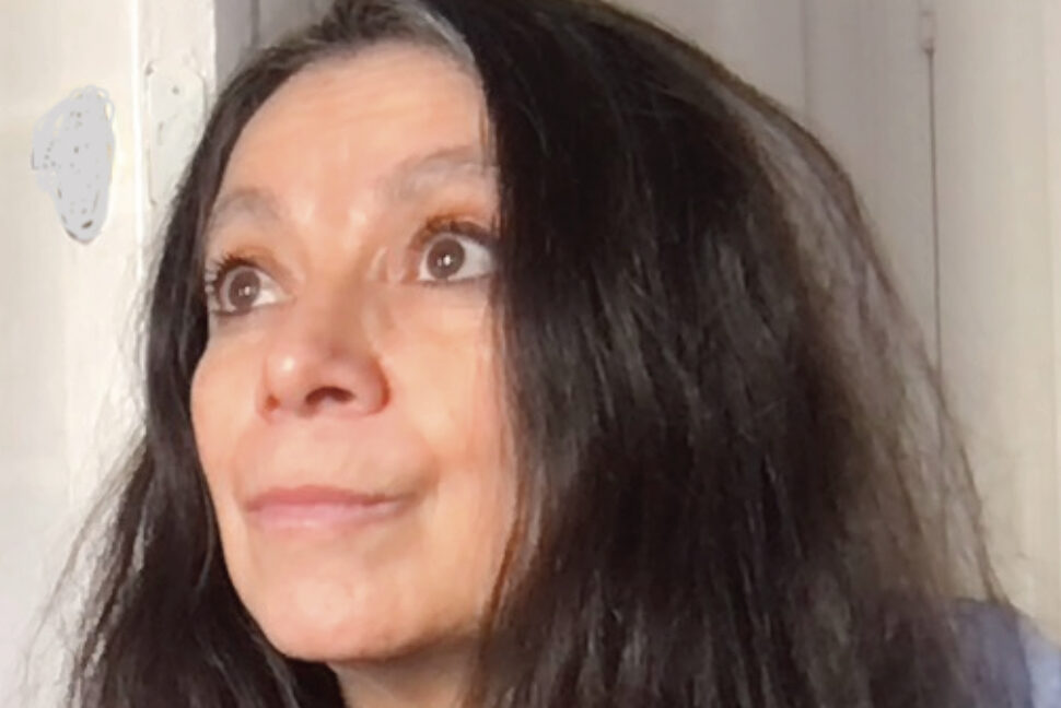 A person with long, dark hair and a thoughtful expression looks upward. They are wearing a blue shirt. The background is neutral and light, creating a serene atmosphere.